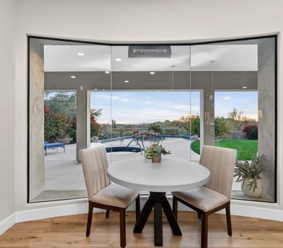 Bright dining nook with large windows framing views of the pool and patio, bringing natural light and Scottsdale outdoor beauty indoors.