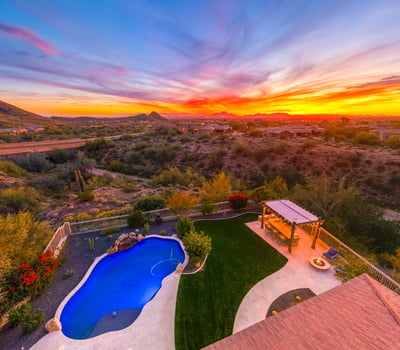 Scottsdale aerial capturing expansive desert scenery, nearby homes, and vibrant sunset skies.