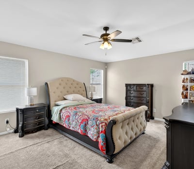 Generous primary bedroom with ceiling fan, soft carpet, and multiple windows. A relaxing retreat designed for comfort in this Casa Grande home.