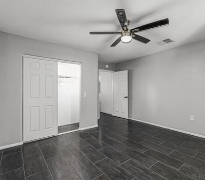 Bedroom with durable tile flooring, ceiling fan, and closet storage. This Sun City home features updated flooring and low-maintenance living.