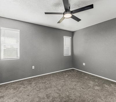 Comfortable bedroom featuring soft carpet, ceiling fan, and bright windows. This Sun City home offers updated finishes and inviting living spaces.