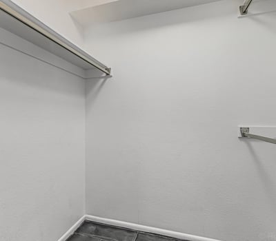 Well-sized walk-in closet with hanging rods and storage space. This Sun City home offers organized living and practical storage solutions.