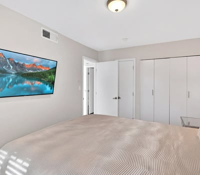 Scottsdale bedroom with wall-mounted TV, neutral tones, and practical layout, offering a comfortable and functional retreat.