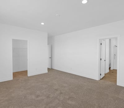 Comfortable primary suite featuring soft carpeting, generous dimensions, and easy access to the ensuite bath and walk-in closet. This inviting space offers a peaceful setting to unwind while enjoying the home's thoughtful layout.