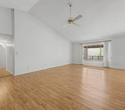 Vaulted ceilings and expansive living space define this bright great room. Wood-look flooring and natural light create an inviting setting perfect for entertaining guests or enjoying quiet evenings at home.