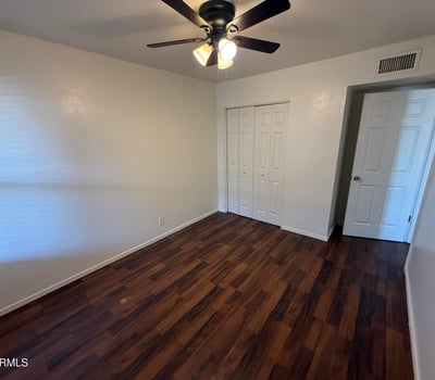 Comfortable bedroom featuring a ceiling fan, large closet, and attractive wood-look flooring. The spacious layout provides flexibility for bedroom furnishings while maintaining a bright and inviting atmosphere.