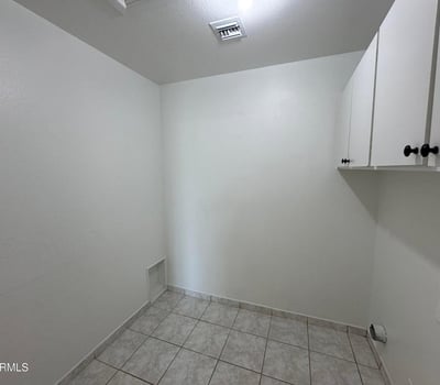 Spacious utility and laundry area featuring built-in cabinetry, durable tile flooring, and plenty of room for storage. A practical addition that supports organized living.