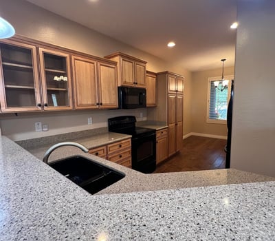 Spacious kitchen offering custom wood cabinetry, ample countertop space, breakfast bar seating, generous storage, and an open layout connecting seamlessly with the home's main living spaces.