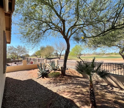 Backyard overlooking the fairway with mature desert trees, attractive landscaping, decorative stone accents, and scenic mountain views. This premium outdoor setting offers both privacy and breathtaking natural surroundings.