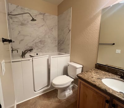 Well-appointed guest bathroom featuring a convenient walk-in tub, updated vanity, durable tile flooring, and attractive finishes that provide comfort, accessibility, and everyday functionality.