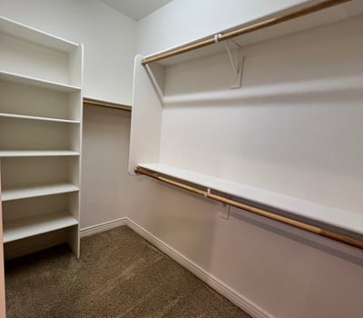 Large walk-in closet complete with built-in shelving, multiple hanging sections, and spacious storage designed to keep clothing and accessories neatly organized.