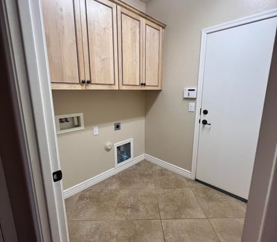 Dedicated laundry room with custom cabinetry, tile flooring, utility hookups, and extra storage space for household essentials, adding convenience to everyday living.