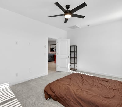Relax in this inviting primary suite featuring plush carpeting, soaring ceilings, ceiling fan, abundant natural light, and easy access to the ensuite bathroom and walk-in closet.
