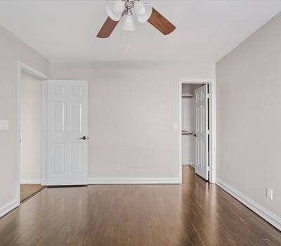 This spacious bedroom offers attractive wood flooring, neutral finishes, ceiling fan, and convenient access to nearby storage. A flexible room that adapts to your needs.