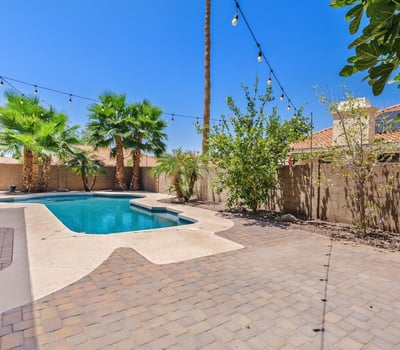 Wide paver patios, lush landscaping, and a sparkling pool create a welcoming outdoor space for gatherings, dining, and enjoying Arizona's beautiful weather in Chandler.