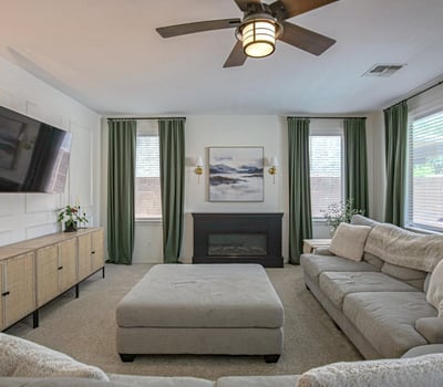 Inviting family room featuring a cozy fireplace, elegant accent wall, large windows, and an open layout. A perfect space to gather, unwind, and enjoy everyday comfort in this Waddell home.