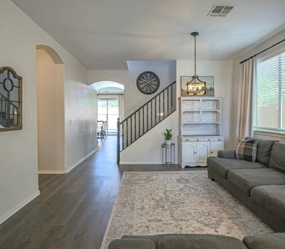 Comfortable living room with updated flooring, elegant lighting, and an open floor plan that creates a warm and welcoming atmosphere for everyday living and entertaining.