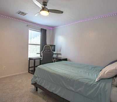 Spacious upstairs bedroom featuring plush carpeting, a ceiling fan, and an open layout with plenty of room for larger furnishings. A comfortable and flexible living space that complements this thoughtfully designed Waddell home.