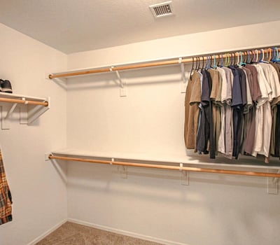 Generous walk-in closet with multiple clothing rods and abundant storage capacity, creating an organized and functional extension of the spacious primary suite.