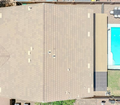 Bird's-eye view showcasing the property's backyard with a sparkling pool, covered patio, lawn area, and low-maintenance landscaping. An excellent aerial perspective of this Waddell home's outdoor amenities.