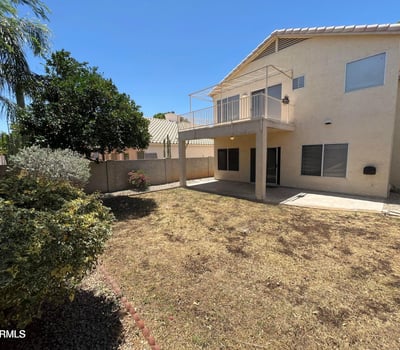 Relax or entertain in the private backyard featuring a covered patio, elevated balcony, mature landscaping, and plenty of outdoor space to enjoy Arizona living in Gilbert.