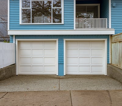 Spacious dual garage with ample storage, featuring a textured concrete driveway and modern architectural design.