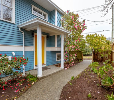 Bright and inviting entrance with colorful landscaping, leading to a well-maintained home in a peaceful neighborhood.