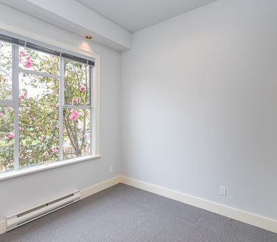 Bright room featuring a large window that offers natural light and views of blooming greenery.