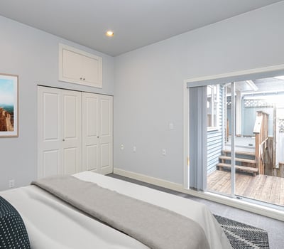 Bright bedroom features sliding doors leading to a private outdoor deck, perfect for relaxation and enjoyment.