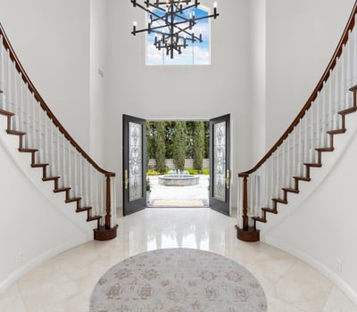Welcome to this striking foyer featuring a grand staircase and inviting double front doors that open to scenic views.