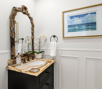 Downstairs Guest Bath-This inviting bathroom features a unique stone vanity , custom wainscoting and coastal-themed artwork, enhancing its modern appeal.