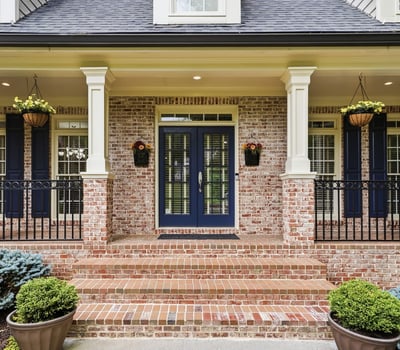 Welcoming entrance features a brick facade, dual blue doors, and attractive landscaping for a polished look.