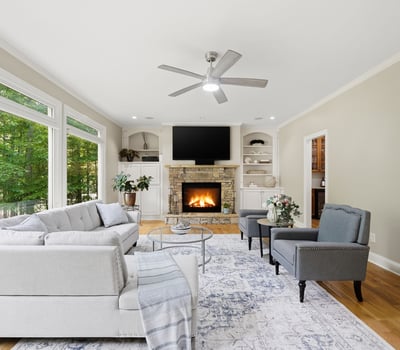 Bright and inviting living space featuring large windows, a cozy fireplace, and modern furnishings.