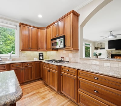 Bright kitchen featuring rich wood cabinetry, spacious countertops, and views of the landscaped outdoor area.