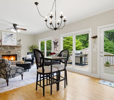 Spacious living area features a cozy fireplace and direct access to a private deck surrounded by greenery.