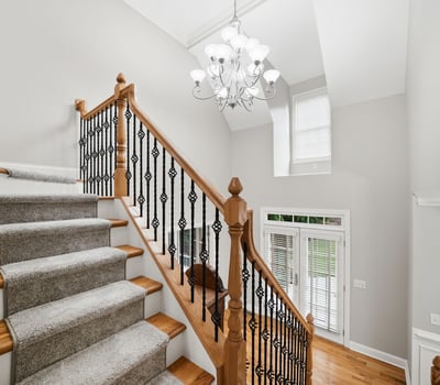 Bright and inviting entryway features a spacious staircase with elegant railings and abundant natural light.