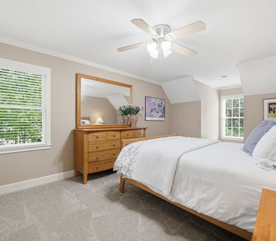 Bright and airy bedroom featuring natural light, modern ceiling fan, and ample storage in a cozy setting.