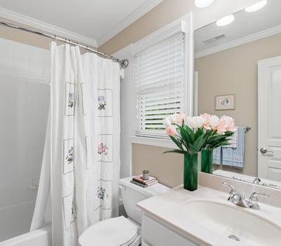 Bright bathroom featuring modern fixtures, a tub-shower combo, and fresh flowers enhancing the inviting atmosphere.