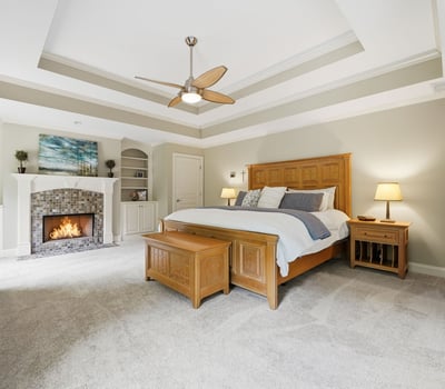 This spacious master bedroom features vaulted ceilings, a cozy fireplace, and ample built-in storage solutions.