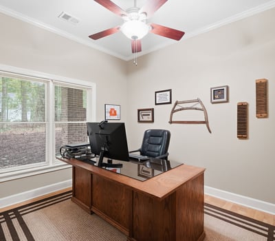 Bright home office featuring a spacious desk, ample natural light, and a tasteful decor theme.