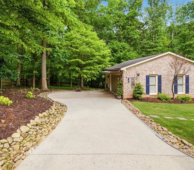 Discover a welcoming home nestled among lush greenery, featuring a spacious driveway and inviting outdoor spaces.