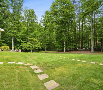 Expansive backyard featuring a winding stone pathway, surrounded by mature trees for added privacy and greenery.