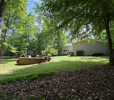 Spacious yard surrounded by lush trees, perfect for outdoor gatherings and entertaining in a private setting.