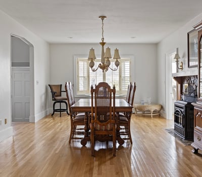Spacious dining area features ample natural light, classic furnishings, and a cozy fireplace for gatherings.
