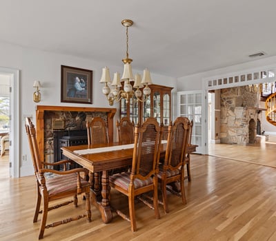 Spacious dining area features a classic table set, surrounded by natural light and detailed woodwork throughout.