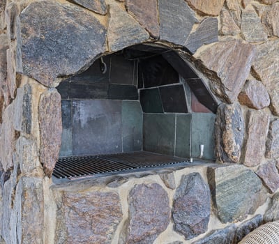 Discover a unique outdoor space featuring a robust stone fireplace, perfect for gatherings and cooking.