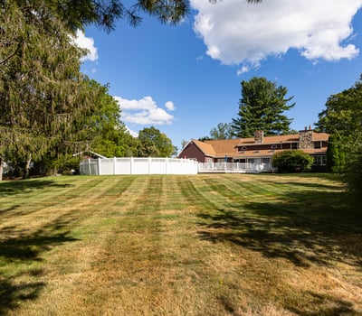 Spacious property featuring a wide-open lawn and a large, inviting home surrounded by lush greenery.