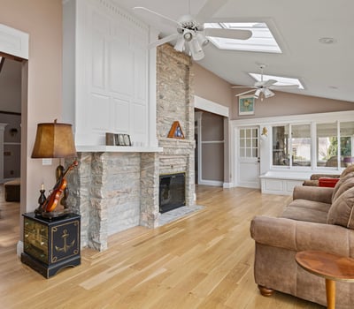 Bright and airy living space featuring a stone fireplace and large windows, perfect for entertaining or relaxing.