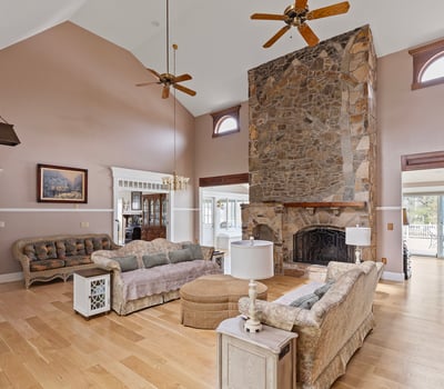 Spacious living area features a stunning stone fireplace and large windows, perfect for natural light.