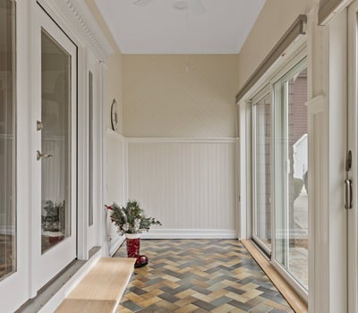 Bright entryway featuring unique herringbone floors, large windows, and ample natural light, ideal for welcoming guests.